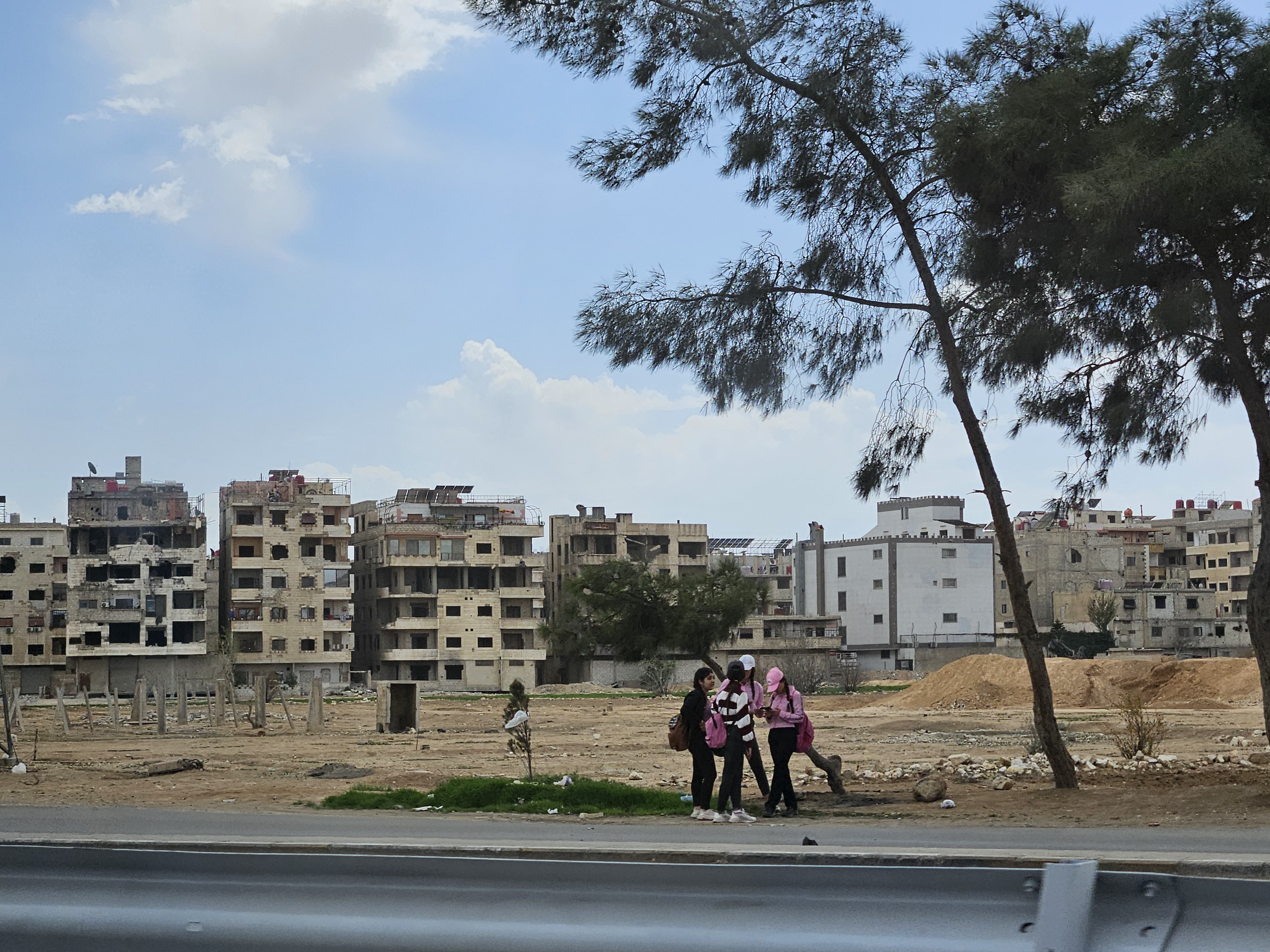 Landscape with destroyed houses and group of young people standing infant