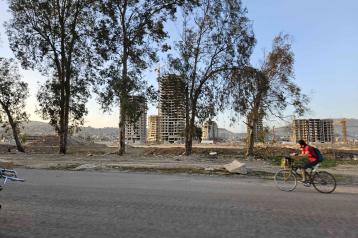 Man on a bicycle on the road in Syria, trees on the background